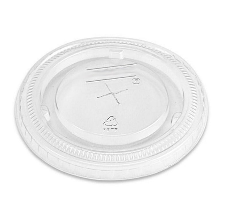 May include: Clear plastic lid for a cup or container. The lid has a raised lip around the edge and a small recycling symbol in the center.