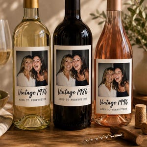 May include: Three glass wine bottles with custom labels featuring a photograph of two smiling people. The labels display the text Vintage 1976, 1986, and 1996, followed by the phrase AGED TO PERFECTION. The bottles contain white, red, and rose wine.