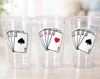 Può includere: Tre bicchieri di plastica trasparente con disegni di carte da gioco. Ogni bicchiere presenta una mano di poker diversa: un colore, un full e una scala. Le carte hanno semi rossi e neri, con cuori, picche e quadri.
