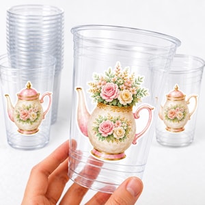 May include: Clear plastic cups featuring a floral teapot design. The teapot is adorned with pink and yellow roses and foliage. These cups are suitable for a tea party or garden gathering.