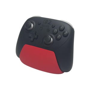 May include: A black wireless video game controller for Nintendo Switch featuring a prominent red lower grip section. The device includes two analog sticks, a directional pad, four action buttons labeled A, B, X, and Y, and the Nintendo Switch logo.