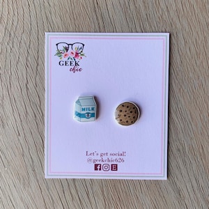 May include: A pair of earrings featuring a milk carton and a chocolate chip cookie. The earrings are on a white card with the text "Geek chic" and "Let's get social! @geekchic626 f o E".