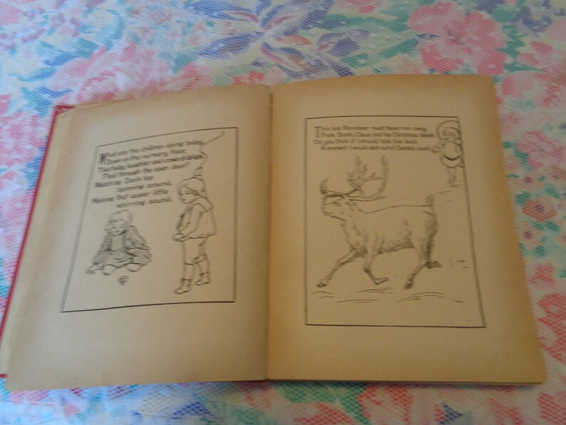 May include: An open vintage book with red binding, featuring black and white illustrations and text. One page shows a reindeer, the other depicts children. The illustrations are in a classic storybook style.