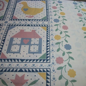 May include: White fabric with a repeating pattern of squares featuring a yellow duck, a house with a pink roof, and a basket. The design includes floral borders with pink, blue, and yellow flowers, and small heart and triangle accents.