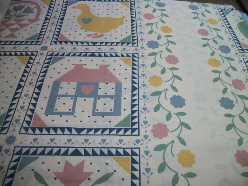 May include: White fabric with a repeating pattern of squares featuring a yellow duck, a house with a pink roof, and a basket. The design includes floral borders with pink, blue, and yellow flowers, and small heart and triangle accents.