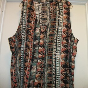May include: A sleeveless vest with a geometric pattern in shades of brown, orange, blue, and white.