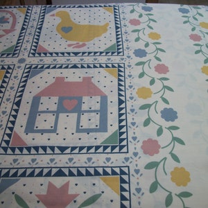 May include: A white fabric with a repeating pattern of squares featuring a house, duck, and floral basket. The design includes blue, pink, yellow, and green accents, with a border of flowers and vines.