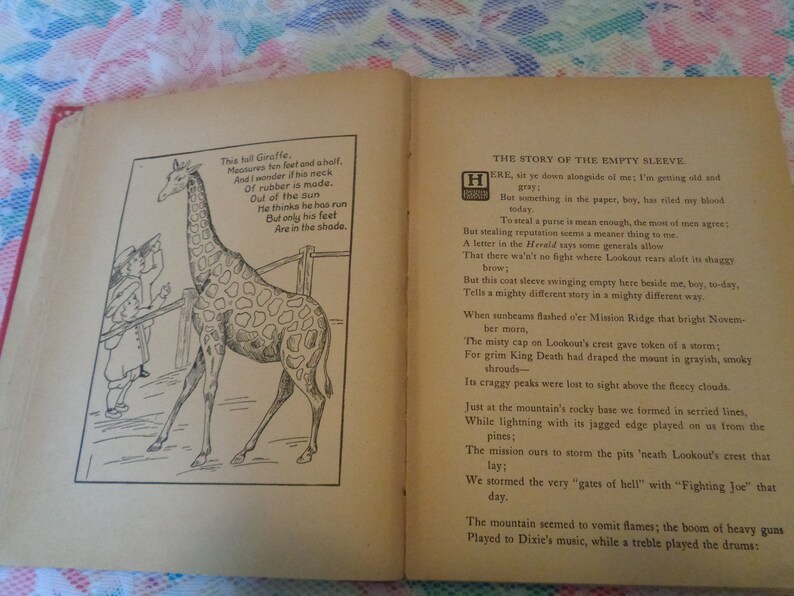 May include: Open book with illustrations and text. One page features a giraffe cartoon with a poem. The opposite page contains a poem titled "THE STORY OF THE EMPTY SLEEVE". The book's pages are aged with a red spine.