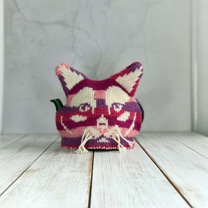 a knitted tea cosy showing a cat face