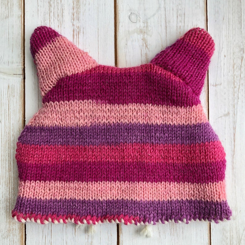 the back of a pink striped cat knitted tea cosy