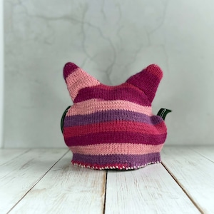 The back of a pink striped knitted tea cosy