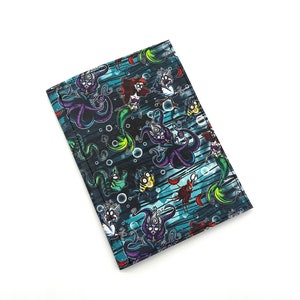 May include: A black fabric wallet with a colorful print of cartoon mermaids, sea creatures, and bubbles. The print features a dark blue, green, purple, and red color scheme.