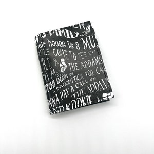 May include: Black and white wallet with a repeating pattern of text that says "Their house is a museum, people come to see 'em,  ri, um, the Addams,  witches shall on a broomstick you can,  wanna pay a call on the Addams, and a kookie..."