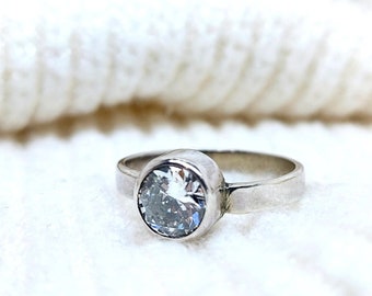May include: A silver ring with a large, clear, round gemstone.