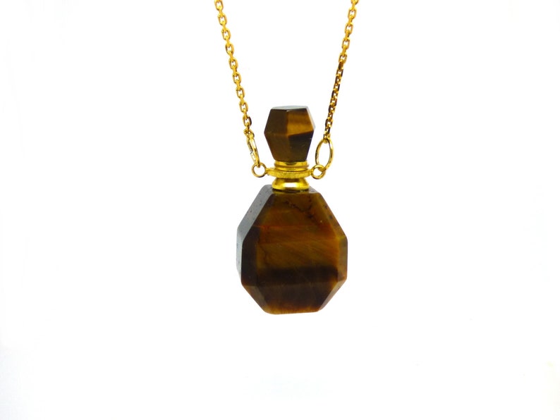 Puede incluir: Un collar de cadena dorada con un colgante de ojo de tigre marr&oacute;n y dorado en forma de botella.