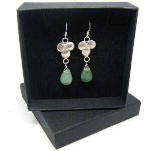 Peut inclure: Une paire de boucles d'oreilles pendantes en argent avec un groupe de petits disques en argent et une seule pierre verte en forme de larme suspendue &agrave; chaque boucle d'oreille.