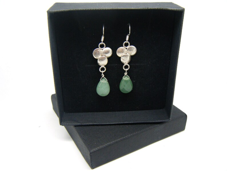 Peut inclure: Une paire de boucles d'oreilles pendantes en argent avec un groupe de petits disques en argent et une seule pierre verte en forme de larme suspendue &agrave; chaque boucle d'oreille.