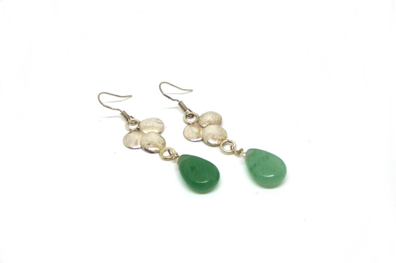 Peut inclure: Une paire de boucles d'oreilles pendantes en argent avec des gouttes de pierres pr&eacute;cieuses vertes. Les boucles d'oreilles pr&eacute;sentent un groupe de quatre disques en argent.