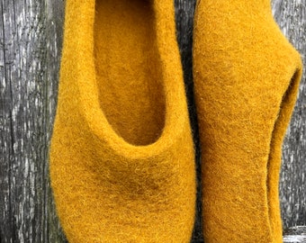 May include: A pair of mustard yellow wool slippers. The slippers are made of felted wool and have a rounded toe.