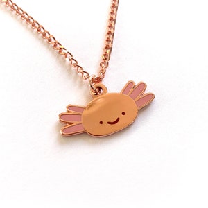 May include: A rose gold necklace featuring a charming axolotl charm. The axolotl is smiling and has pink gills.
