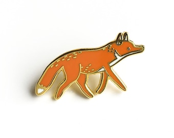 May include: A gold-toned enamel pin featuring a cartoon fox with an orange body and white accents. The fox is walking with its tail curled behind it.