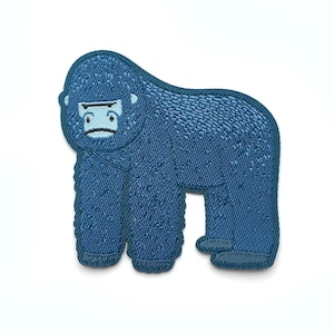 Può includere: Una toppa ricamata blu di un gorilla con un viso semplice.