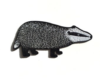 May include: Black and white embroidered iron-on patch of a badger.