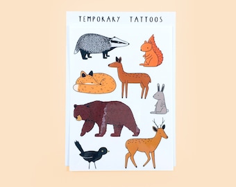 May include: A sheet of temporary tattoos featuring woodland animals. The designs include a badger, squirrel, fox, deer, rabbit, bear, bird, and a deer. The words "TEMPORARY TATTOOS" are printed at the top of the sheet.