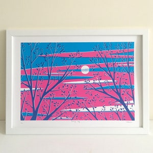 May include: A framed art print featuring a stylized landscape. The artwork showcases a vibrant color palette of pink, blue, and white, depicting a sunset or sunrise scene with silhouetted trees. The print is in a white frame.