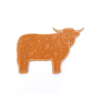 Op de afbeelding: Een bruin geborduurd embleem met een Schotse Hooglander. Het embleem toont de koe in profiel, met gedetailleerde steken die haar lichaam, hoorns en ruige vacht definiëren. Het embleem is bedoeld om op stof te strijken of te naaien.