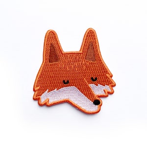 Peut inclure: Écusson brodé représentant une tête de renard stylisée. Le patch est détaillé avec des fils orange, marron, blanc et noir. Le renard a des oreilles pointues et une poitrine blanche duveteuse. Idéal pour décorer vêtements et accessoires.