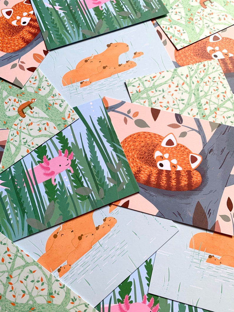 May include: A set of illustrated cards featuring various animals in a nature setting. The cards feature a red panda sleeping in a tree, a red panda with cubs, a capybara with cubs, an axolotl, and a red panda with cubs swimming in a pond.