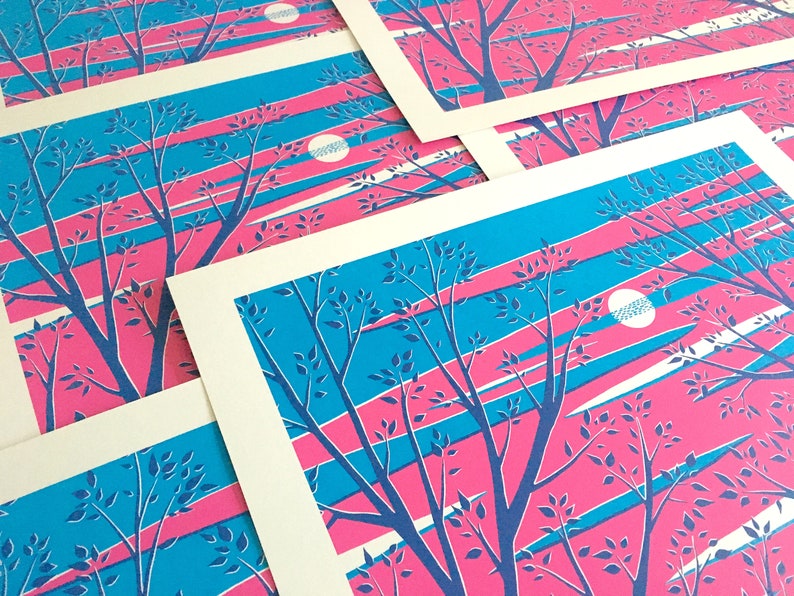 May include: A collection of art prints featuring a stylized landscape. The prints showcase a vibrant color palette of pink, blue, and white. The design includes silhouetted trees and a moon, set against a backdrop of diagonal stripes.