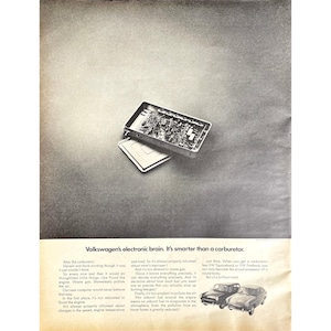 May include: A black and white advertisement featuring a car's electronic brain. The image shows an open metal box with circuit boards and a separate lid. The text reads, "Volkswagen's electronic brain. It's smarter than a carburetor."