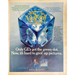 May include: A blue cube with a gold GE logo on the front. The cube has a green dot on the top and a black dot on the bottom. The text "Only GE's got the green dot. Now, it's hard to goof up pictures." is below the cube. The text "The Blue Coat Green Dots General Electric" is at the bottom of the image.