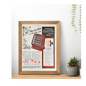 May include: A framed vintage advertisement for an Emerson-Electric Radiant & Fan-Type Heater. The ad features a red heater with a woman pointing at it. Text includes "Chase the Chills...at a flip of the switch" and "Announcing NEW SENSATIONAL".