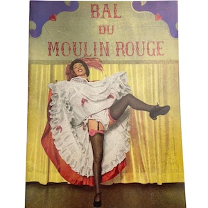 May include: Vintage postcard featuring a dancer in a white ruffled dress with red accents, black stockings, and a garter. The text "BAL DU MOULIN ROUGE" is displayed above the dancer. The background is a yellow curtain.