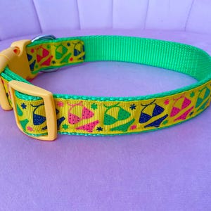 May include: A bright green dog collar with a yellow buckle and a repeating pattern of colorful bikini tops. The bikini tops are in shades of blue, pink, and green on a yellow background.