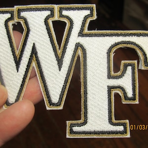 May include: White felt patch with black and gold embroidered letters "WF".