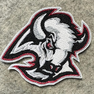 May include: Black and white embroidered patch of a bull's head with red accents. The bull's head is facing forward with its horns pointing up.