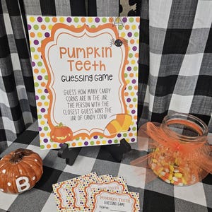 Könnte beinhalten: Ein Halloween-Spielset mit einem Schild mit der Aufschrift "Pumpkin Teeth Guessing Game". Das Schild ist mit orangefarbenen, lila und gelben Punkten und einer Kürbisgrafik verziert. Enthält ein Glas mit Zuckermais, kleine Karten und einen dekorativen Kürbis.