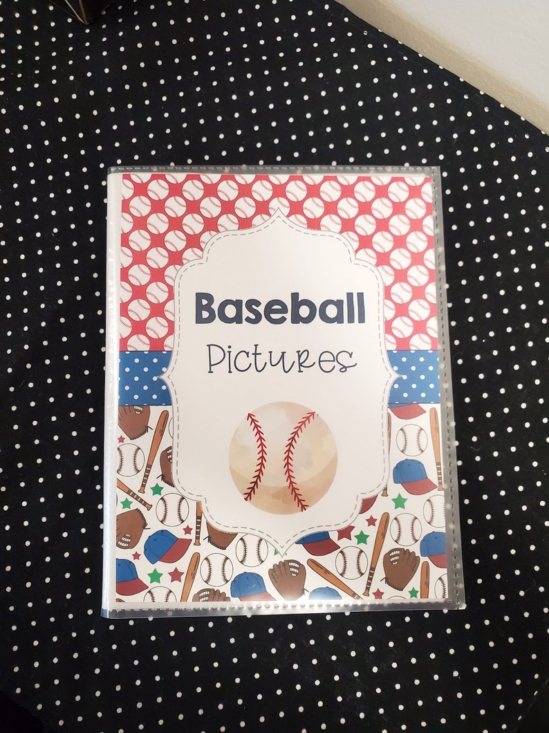 Peut inclure: Un album photo en plastique transparent avec une couverture &agrave; th&egrave;me baseball rouge, blanc et bleu. La couverture pr&eacute;sente un ballon de baseball, des battes, des gants et des casquettes. Le titre de l'album est "Baseball Pictures".