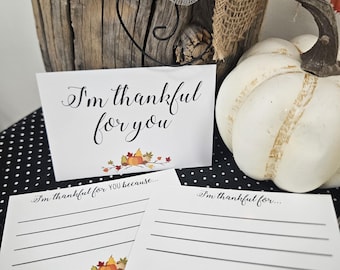 Puede incluir: Tarjetas blancas con el texto "I'm thankful for you" y líneas para escribir. Las tarjetas tienen un diseño de otoño con calabazas y hojas. Una calabaza blanca y elementos decorativos están en el fondo.