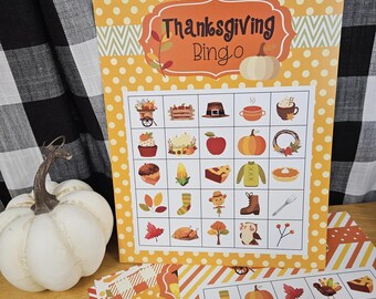 May include: Thanksgiving Bingo game set with a white pumpkin and patterned cards. The Bingo card has a yellow polka dot background with Thanksgiving-themed illustrations. The text "Thanksgiving Bingo" is displayed in an orange banner.