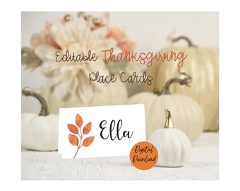Puede incluir: Imagen otoñal con calabazas blancas y arreglos florales. Una tarjeta de sitio con el nombre "Ella" y un diseño de hojas naranjas está en primer plano. También se ven las palabras "Editable Thanksgiving Place Cards" y "Digital Download".