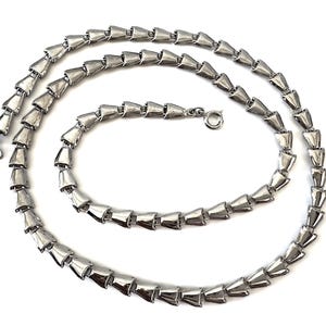 May include: A silver-toned necklace with a repeating geometric design. The necklace is composed of numerous cone-shaped links connected to form a flexible chain. The clasp is a simple hook and eye closure. The jewelry is displayed on a white background.