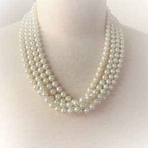May include: A multi-strand pearl necklace with a classic design. The necklace is made of white faux pearls and is perfect for adding a touch of elegance to any outfit.