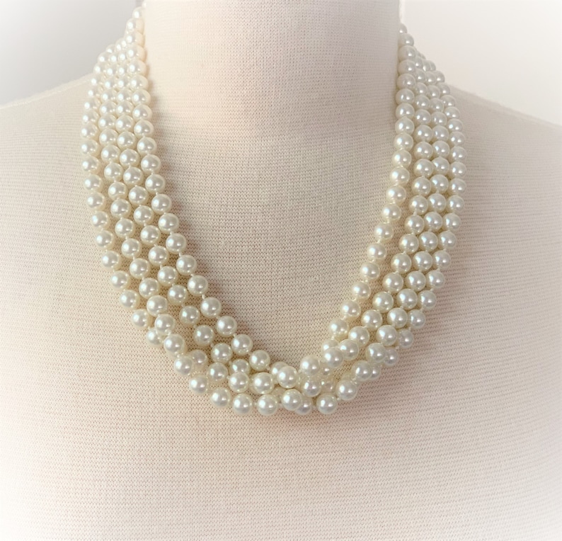 May include: A multi-strand pearl necklace with a classic design. The necklace is made of white faux pearls and is perfect for adding a touch of elegance to any outfit.