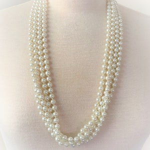 May include: A multi-strand pearl necklace with a classic design. The necklace is made of white faux pearls and is perfect for adding a touch of elegance to any outfit.