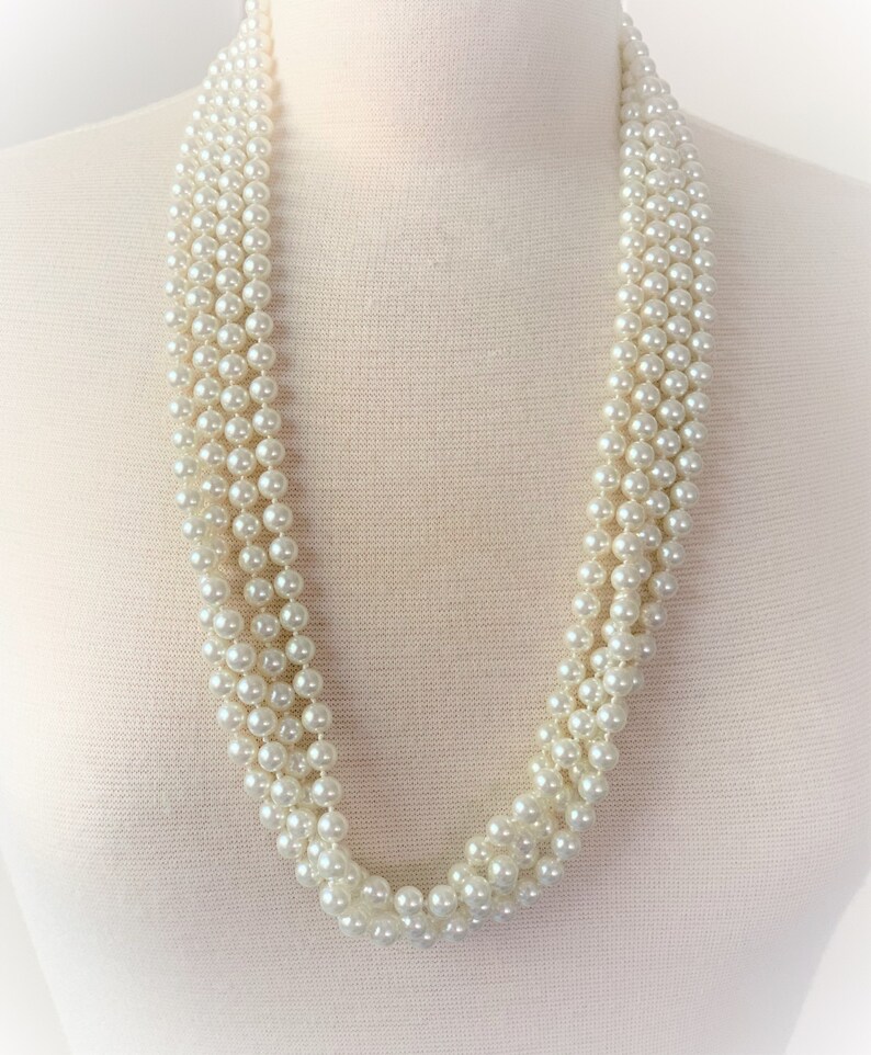 May include: A multi-strand pearl necklace with a classic design. The necklace is made of white faux pearls and is perfect for adding a touch of elegance to any outfit.
